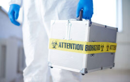Medical case with biohazard held by gloved scientist