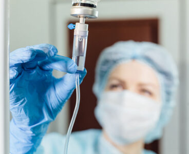 Nurse connecting an intravenous drip in hospital room