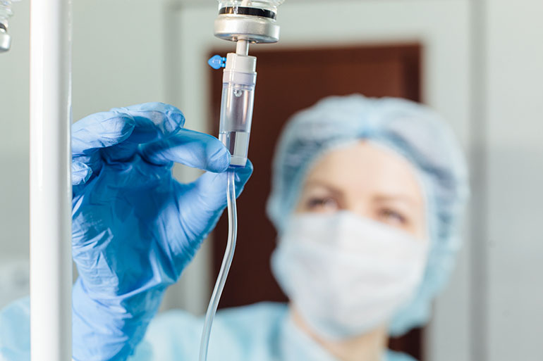 Nurse connecting an intravenous drip in hospital room