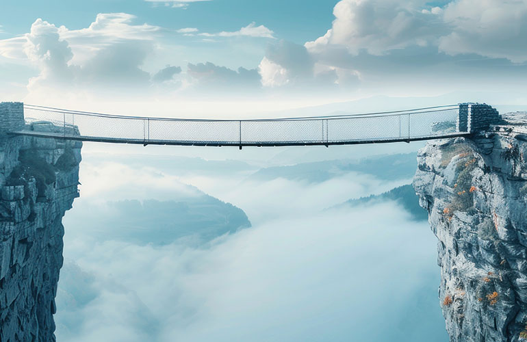 A long suspension bridge over a deep valley with clouds in the background