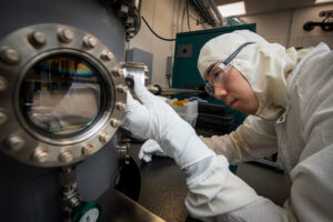 Berkeley Lab graduate student researcher Larry Chen, co-author of the recent Applied Physics Letters study, examines equipment in a specialized clean room for superconducting qubit research.