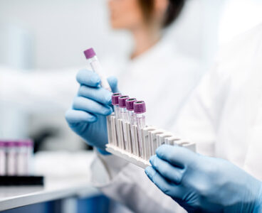 Laboratory assistant putting test tubes into the holder, Close-up view focused on the tubes