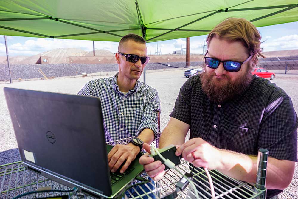 R&D 100 Finalist griDNA: Sandia’s Adrian Chavez (left) and Logan Blakely integrate the edge autoencoder onto a single-board computer at Public Service Company of New Mexico’s Prosperity solar test site. (Photo by Bret Latter)