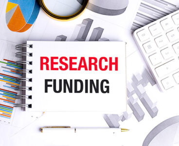 Notebook with a text research funding on financial documents with calculator and pen on white desk .