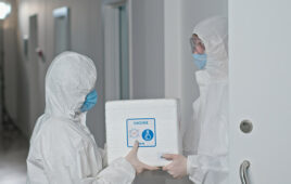 In a sterile environment, two diligent lab technicians exchange a package, emphasizing strict safety protocols