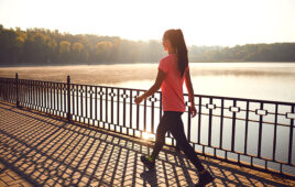 Back view of a runner walking on a road in a park at dawn in summer in autumn.