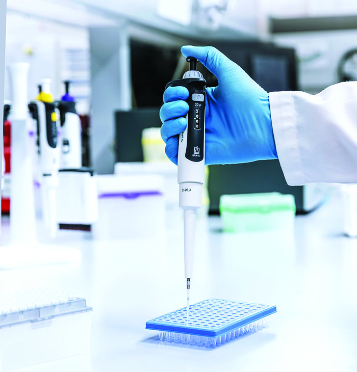 A Transferpette pro micropipette is shown dispensing liquid into a microplate during routine laboratory work.