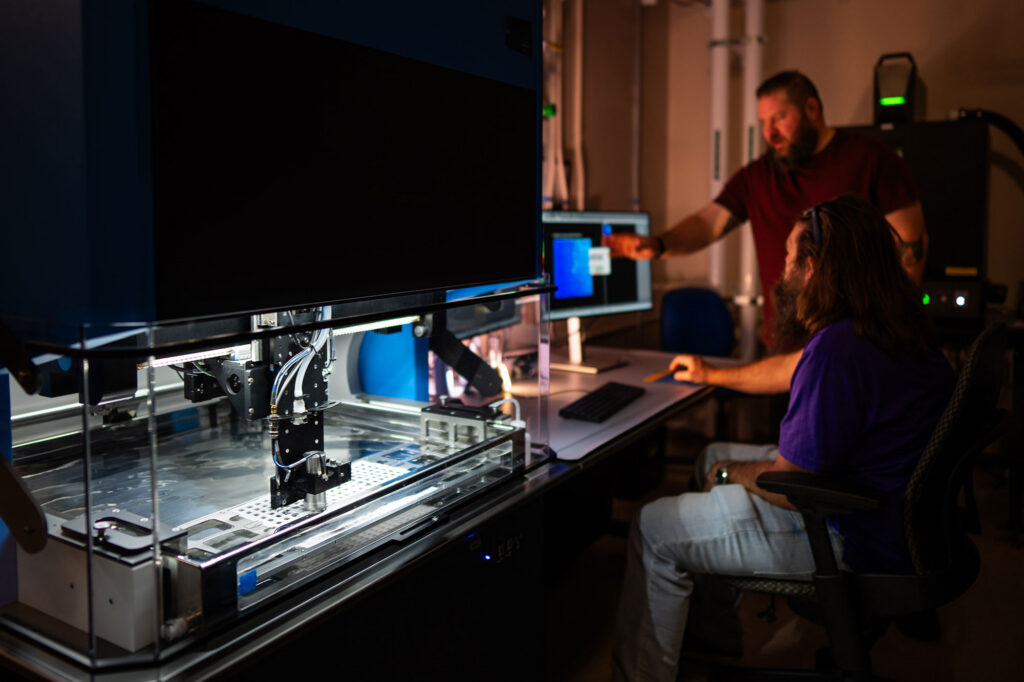 Sandia staff set up a new ultrasonic inspection tool that pairs acoustic imaging with AI-based anomaly detection to inspect ceramic components for nuclear deterrence applications. (Photo by Craig Fritz/Sandia National Laboratories)