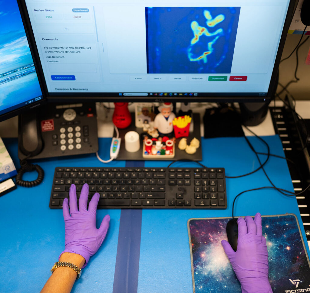 A Sandia technician reviews a scanned image of a ceramic billet at her desktop. In the new workflow, operators review raw images alongside AI-generated anomaly overlays in a web app, with results sorted by anomaly score so the most likely defects surface first. (Photo by Craig Fritz/Sandia National Laboratories)