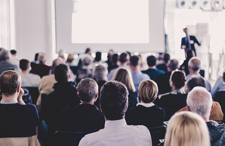 Speaker Giving a Talk at Business Meeting. Audience in the conference hall. Business and Entrepreneurship. Panoramic composition suitable for banners.