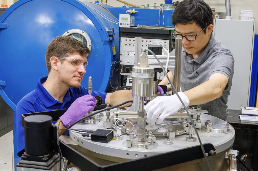 SwRI researchers John Hemmerling, left, and Jianliang Lin work with a deposition chamber used to develop ultra-thin films for solid-state battery interfaces. Credit: Southwest Research Institute