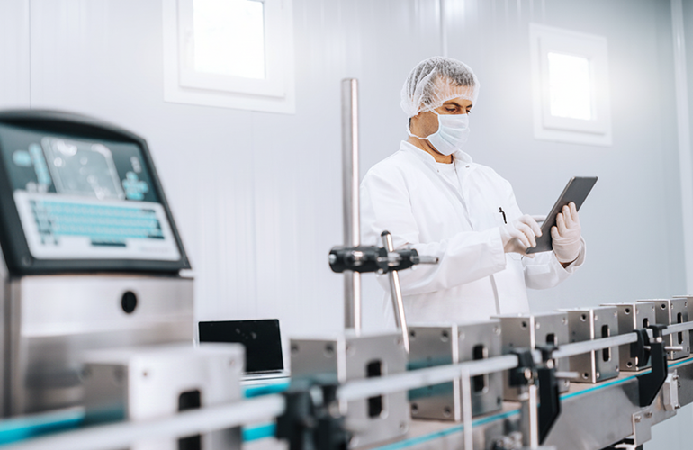 A technician reviews production data beside a medical-device manufacturing line. (Image credit: Adobe Stock; modified using generative AI.)