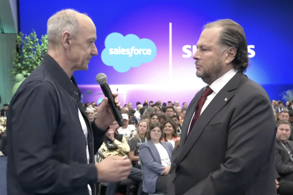Siemens CEO Roland Busch speaks with Marc Benioff in front of Salesforce and Siemens logos