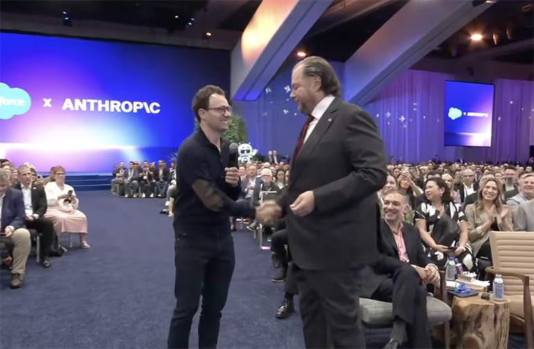 Anthropic CEO Dario Amodei greets Marc Benioff on stage in front of a Salesforce x Anthropic backdrop