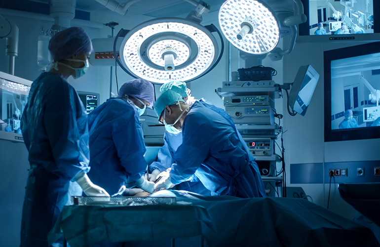 Surgical team operating under overhead lights in a modern operating room