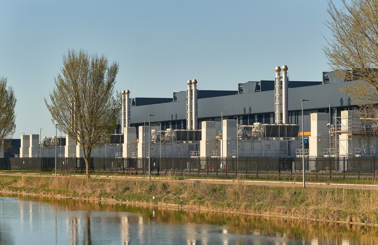 A data center campus with exhaust stacks beside a canal
