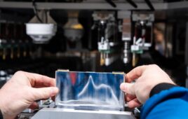 A researcher handles a prismatic battery cell on PNNL’s manufacturing line.