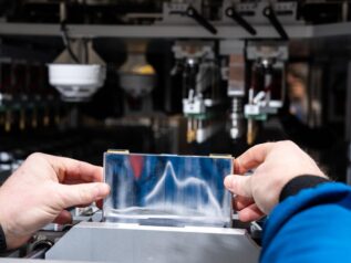 A researcher handles a prismatic battery cell on PNNL’s manufacturing line.
